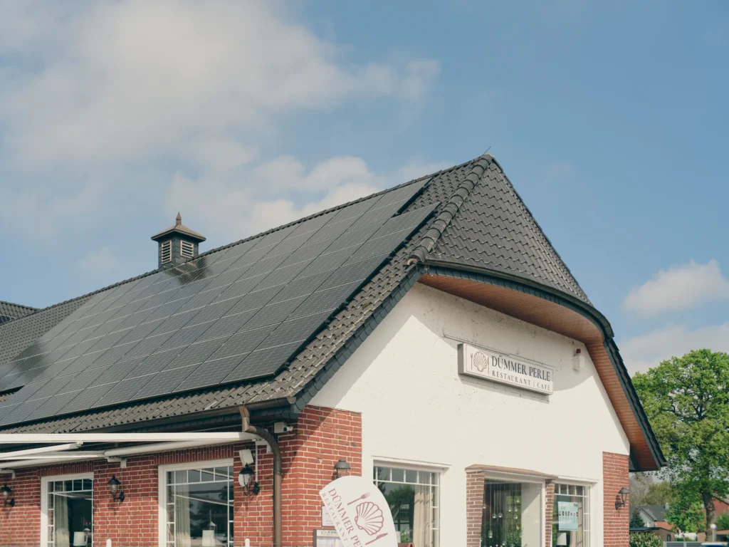 Solar panels on a roof with nearby gutters and downspouts.