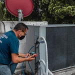 HVAC technician inspecting a residential air conditioning condenser unit.